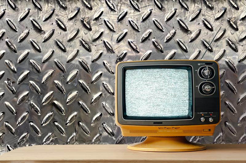 Diamond plate peel and stick wallpaper pattern with retro tv that has static on screen sitting on maple counter top