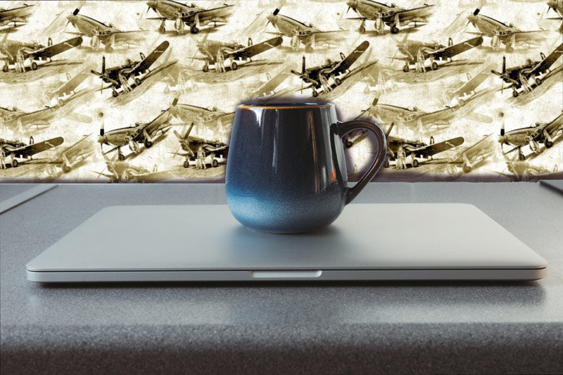 Vintage-Airplane-Peel-and-stick-wallpaper-blue-mug-sits-on-a-closed-silver-laptop